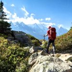 Trekker walking along a rocky Himalayan trail with a backpack and trekking pole
