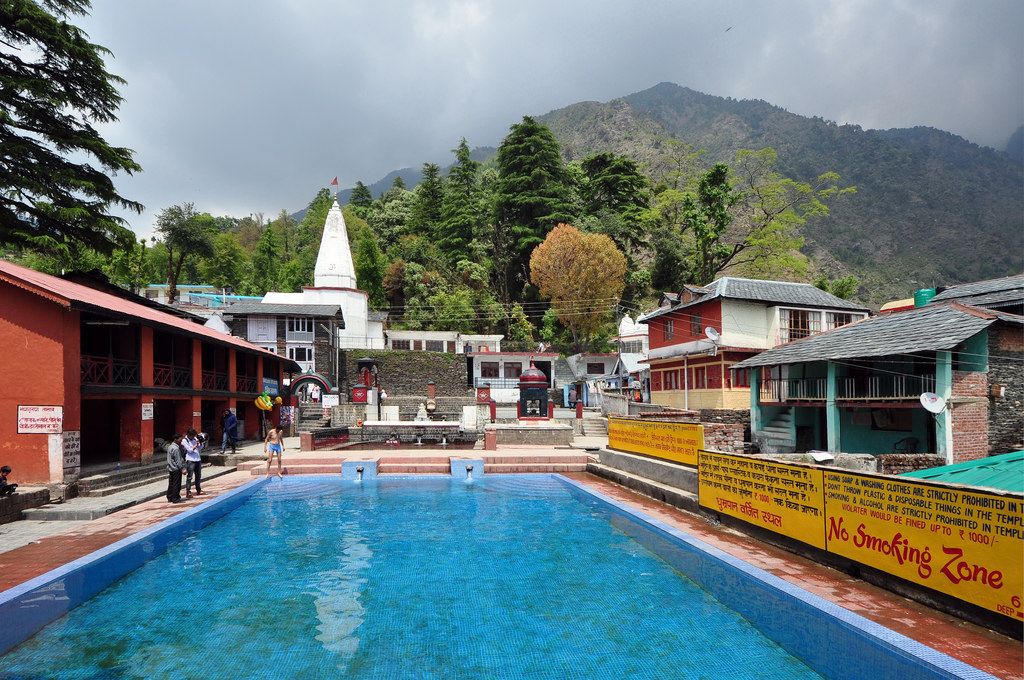 Bhagsunag Temple and sacred pool in Dharamshala, Himachal Pradesh, with mountains in the background.